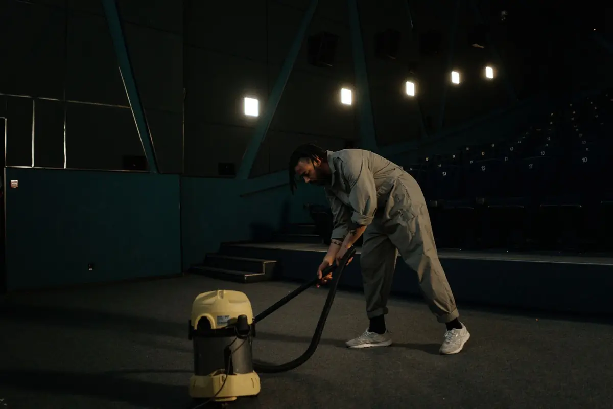 Cleaner vacuuming carpet in a large commercial venue