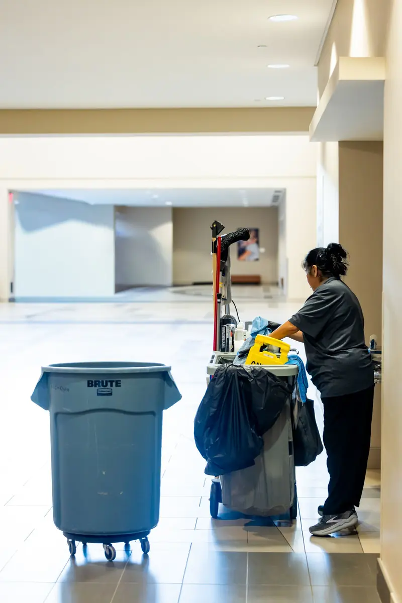 Commercial cleaner with a cleaning trolley in a large building corridor